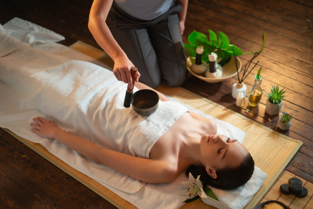 Young woman getting massaging treatment over exotic background. Spa, healthcare and recreation concept